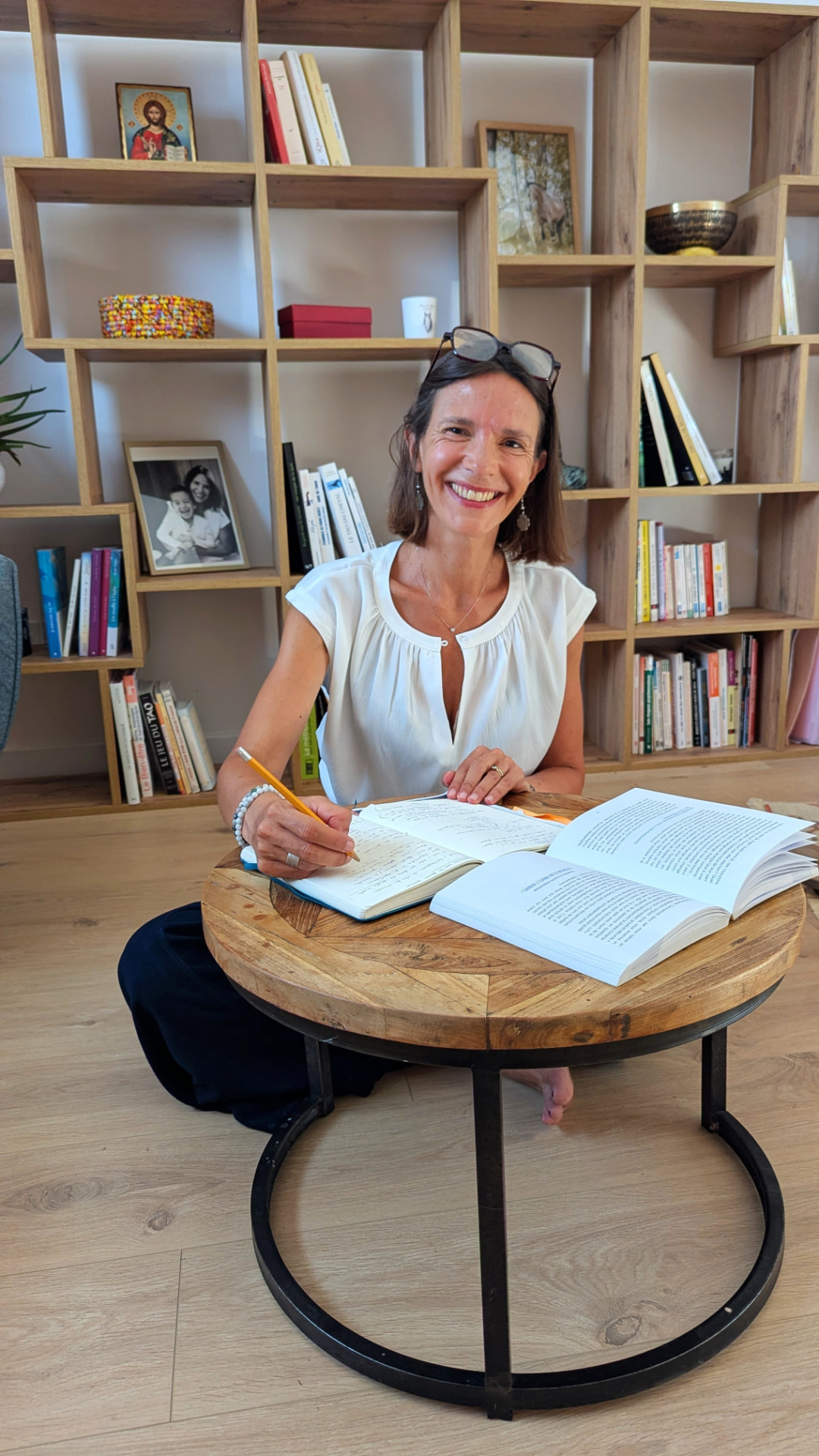 Adeline Gourdon écrivant dans son carnet, assise à une petite table ronde en bois