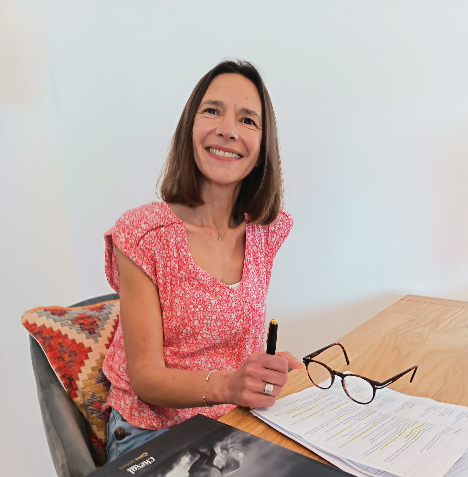 Adeline Gourdon assise à son bureau, souriante, un stylo à la main